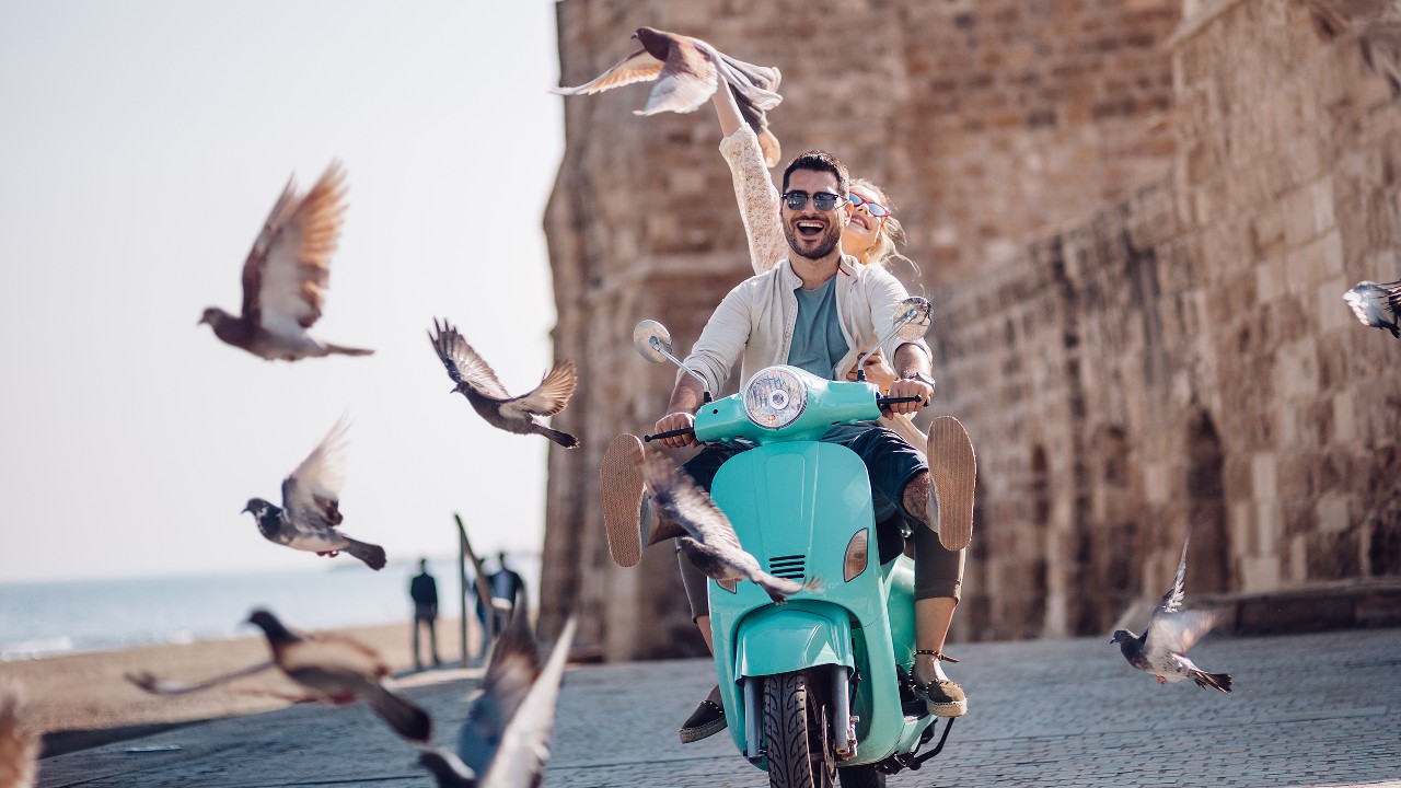 A young couple riding a motor excitedly with several birds taking off;  image used for HSBC Sri Lanka credit card other offer page