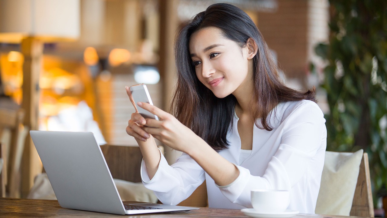 A women is using smartphone and laptop; image used for HSBC Sri Lanka ways to bank branch banking